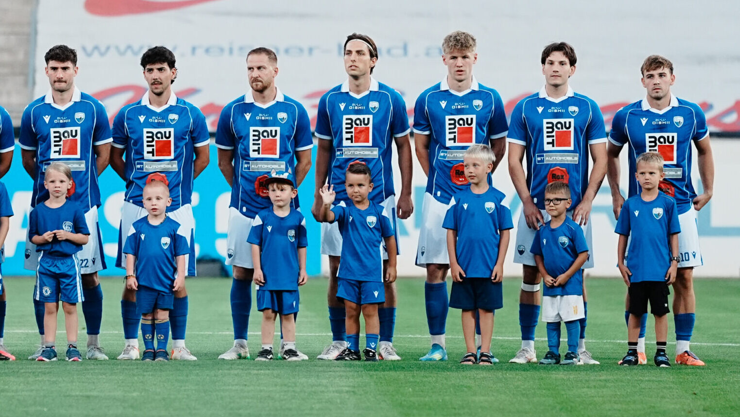 Fußballmannschaft mit Kindern in blauen Trikots auf einem Rasen in Österreich